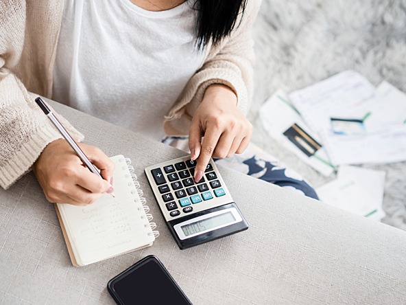 woman calculating personal finances using calculator and notebook